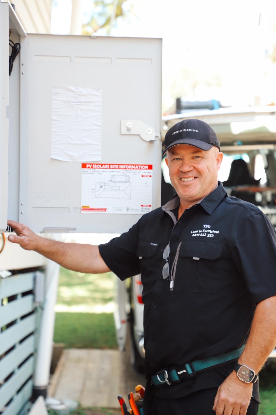 Tim from Lead In Electrical at a switchboard beside his work van